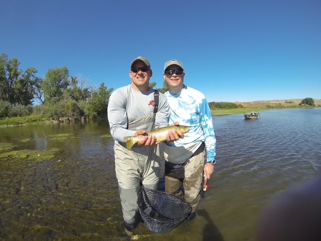 Two anglers holding a trout on a sunny Utah waterway