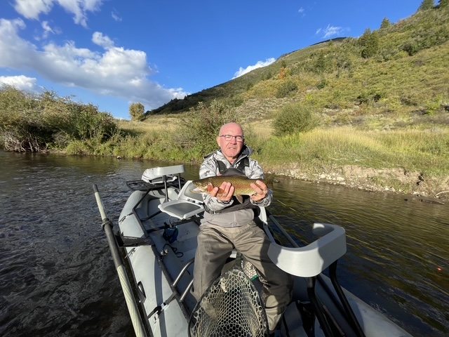 Angler holding a trout from a drift boat